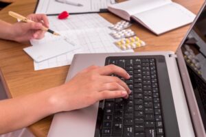 doctors-hands-typing-laptop-filling-prescription_359031-5228