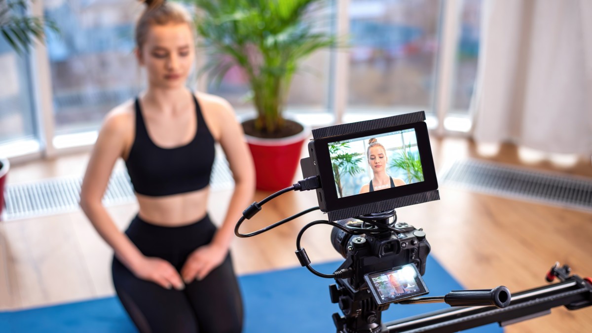 professional-camera-with-external-display-recording-young-blonde-woman-sportswear