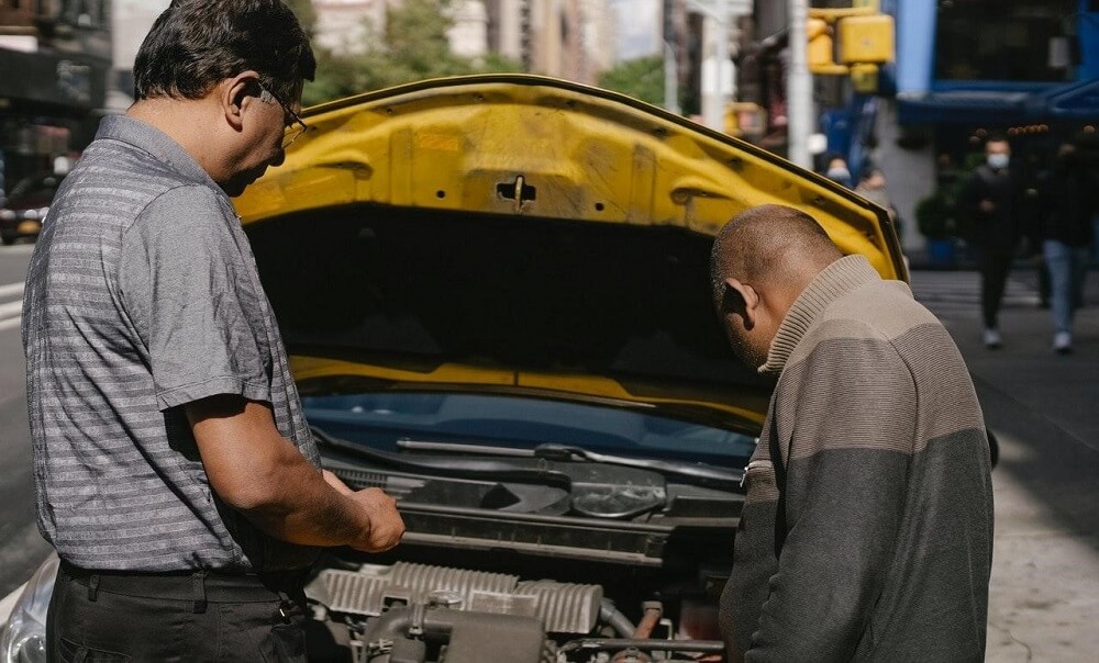 ethnic-mechanic-checking-car-standing-near-man
