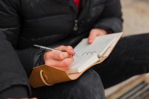 close-up-guy-writing-notebook