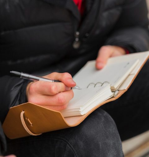 close-up-guy-writing-notebook