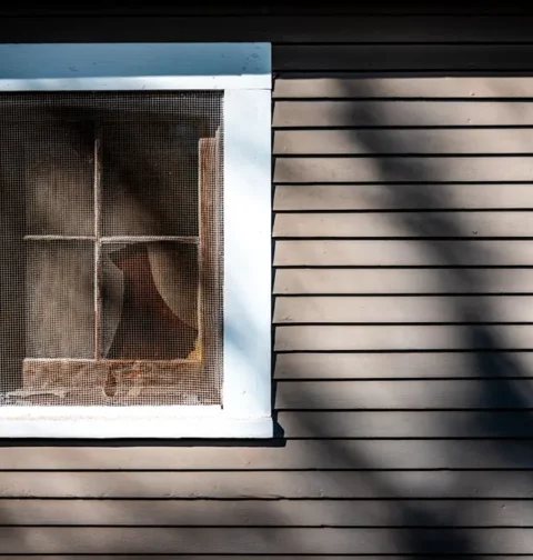 Wall of a House with a Window Covered with Net