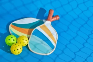 two-pickleball-paddles-with-some-balls-them-with-shadow-net-front-blue-background